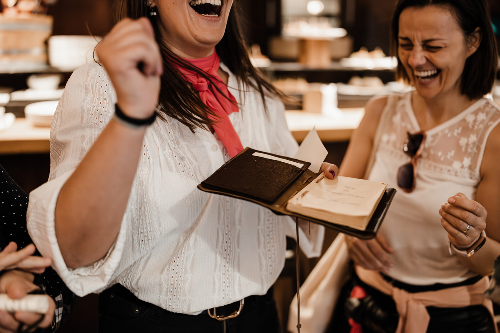 Two women, one holding columbus his travel logbook. They are smiling, look happy, are celebrating. They won the city game called The Legacy of Columbus.